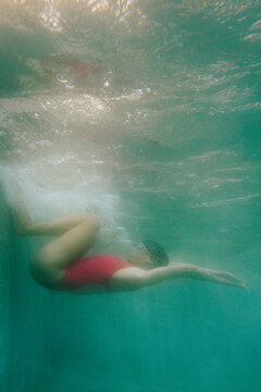 Woman in a red sports swimsuit swims in the pool