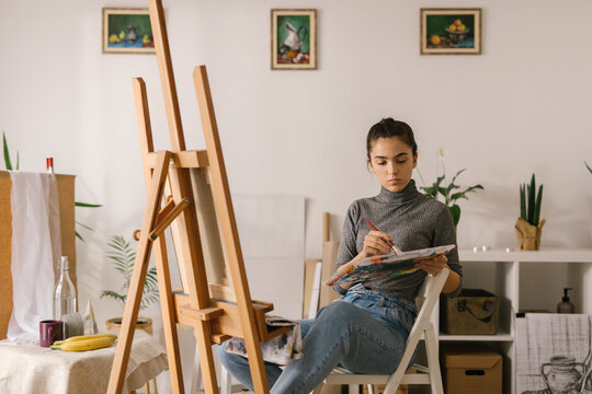Young woman mixing watercolors for painting at home