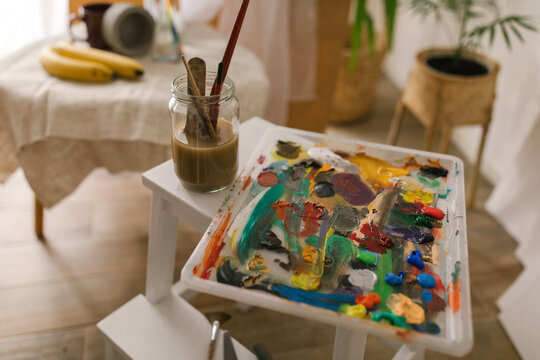 Color palette and brushes in the water on the table