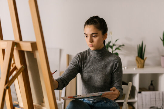 Young female artist painting at home