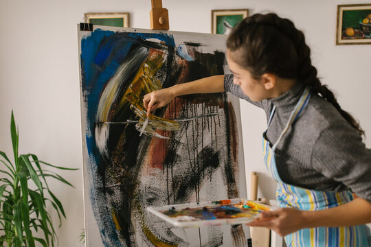 Female artist painting on canvas in art studio