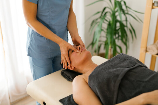 Unknown massage therapist doing face massage at spa