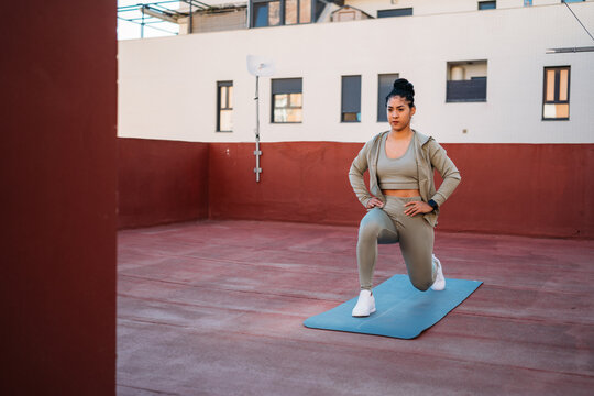 Serious woman doing lunges on sports mat