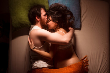 Kissing pregnant couple on bed