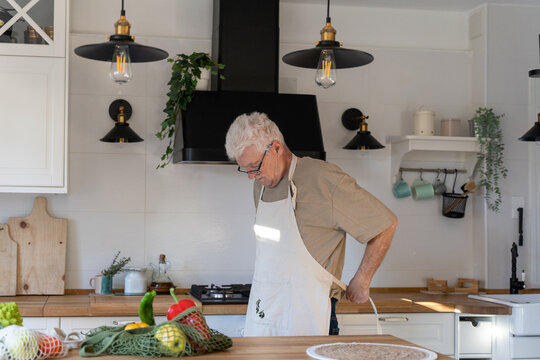 Senior man wearing apron in the kitchen to cook