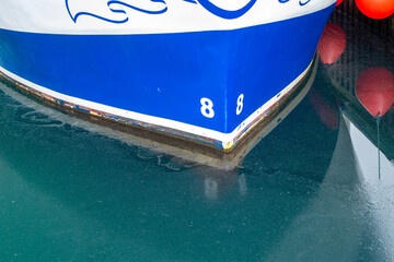 The bow or front of a blue and white color metal fishing boat. The water is at the 8 meter...