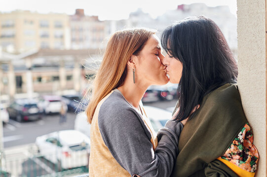 Lesbian couple kissing on their balcony