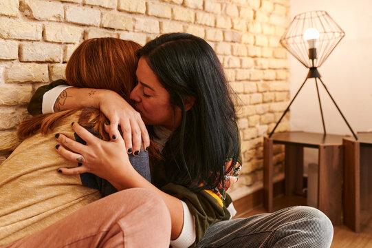 Lesbian couple hugging at home
