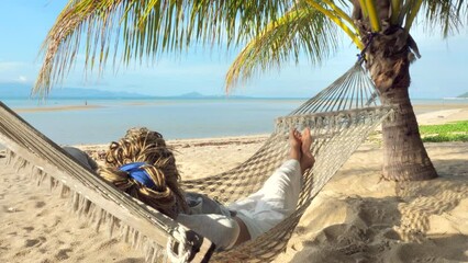 Relaxed woman swinging in a hammock at sand beach of Thailand