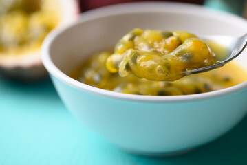 Passion fruit juice in bowl with spoon for eating on pastel color background, Tropical fruit in summer season