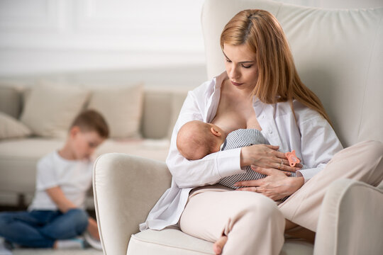 Mom breastfeeds baby. Mom watches the baby as she eats.