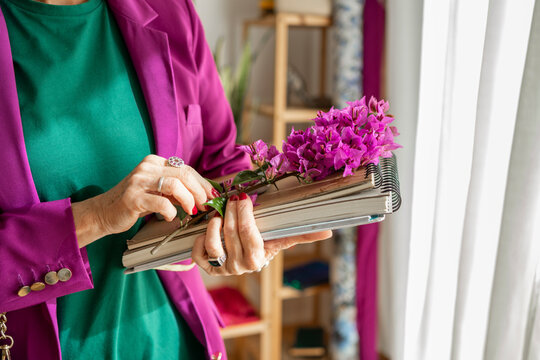 Elegant female holding notebooks and flowers