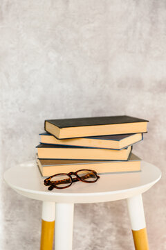 Hardback books on a table with spectacles