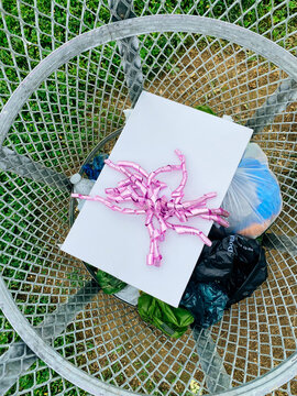 Package with pink bow thrown away in rubbish bin