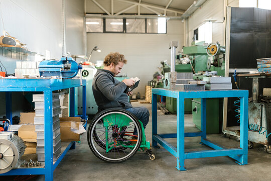 Man In A Wheelchair Working In His Workshop