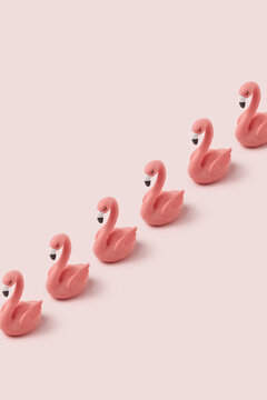 Diagonal row of flamingo figures on pastel background