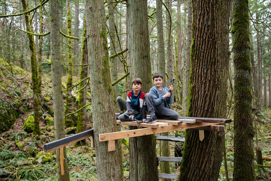 Two kids looking at camera on tree fort.