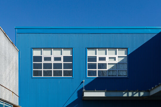 Facade of a blue aluminum building with two windows