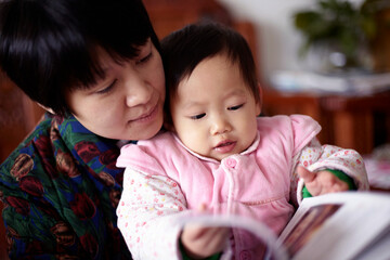 Cute asian baby and mother are reading picture book
