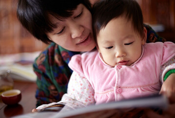 Cute asian baby and mother are reading picture book
