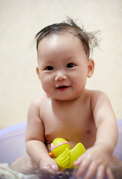 Asian little baby playing with toys in bath

