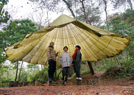 Asian family playing under large parachute outdoors

