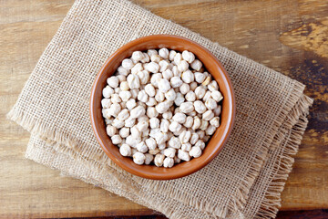 Raw organic chickpeas grains in bowl over rustic wooden table