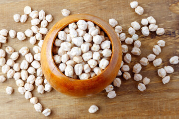 Raw organic chickpeas grains in bowl over rustic wooden table