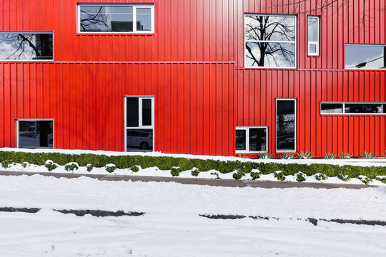 A red colored tin building with windows and snow 