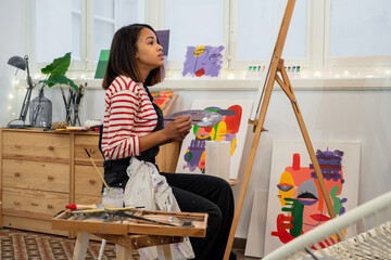 Woman painting on easel in workshop