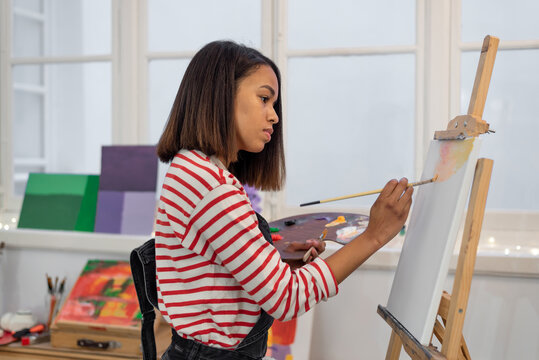 Woman painting on easel in workshop