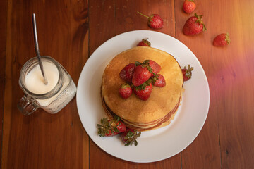 Plate of hot cakes and strawberries on a wood table
