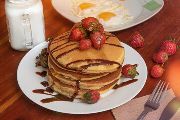 Plate of hot cakes and strawberries on a table