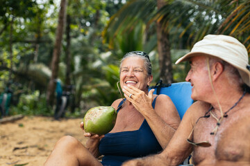 Obraz premium Senior woman laughing while drinking a coconut