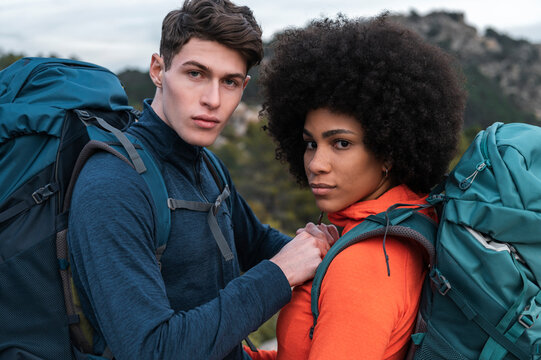 Diverse traveling couple looking at camera in nature 