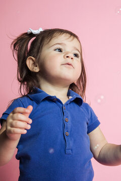 Little girl smiling in studio playing with bubbles