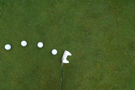 Golfer's POV of putter and a row of balls