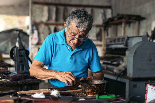 Senior shoemaker dyeing some soles