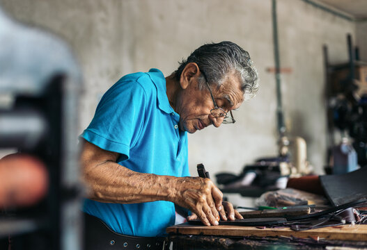 Hispanic senior shoemaker working in his workshop