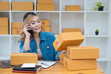 SME business starting a small business A female entrepreneur works with boxes and laptops to accept and monitor online orders to prepare the boxes. Selling to customers. Online SME business idea.