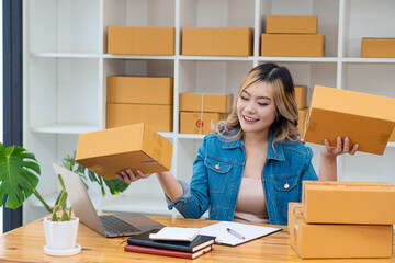 Fototapeta na wymiar SME business starting a small business A female entrepreneur works with boxes and laptops to accept and monitor online orders to prepare the boxes. Selling to customers. Online SME business idea.