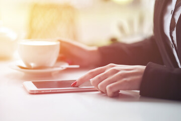 Business woman hands using smart phone and cup of coffee.
