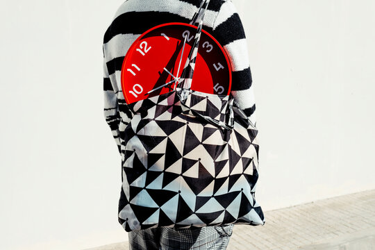 man carries a red clock in a textile bag