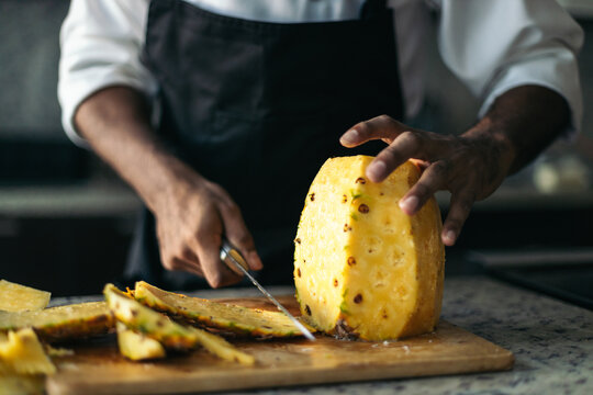 Anonymous pastry chef cutting a pineapple - Powered by Adobe