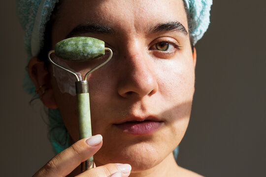 Portrait of Young Confident Woman Using a Jade Roller