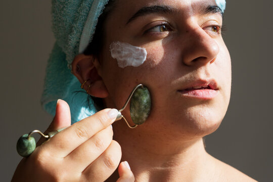 Portrait of Young Confident Woman Using a Jade Roller