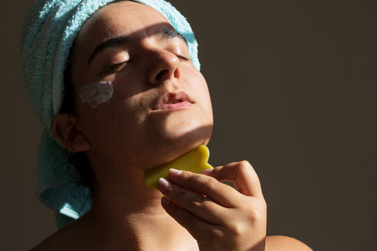 Beautiful woman doing facial massage with gua sha