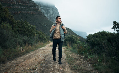 Let your feet wander, your eyes marvel and your soul ignite. Shot of a young man hiking through the...