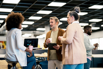 Coworkers drinking coffee and talking in office