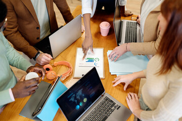 Unrecognizable colleagues analyzing charts at table